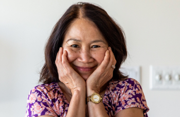 A woman smiling with her hands held to her face