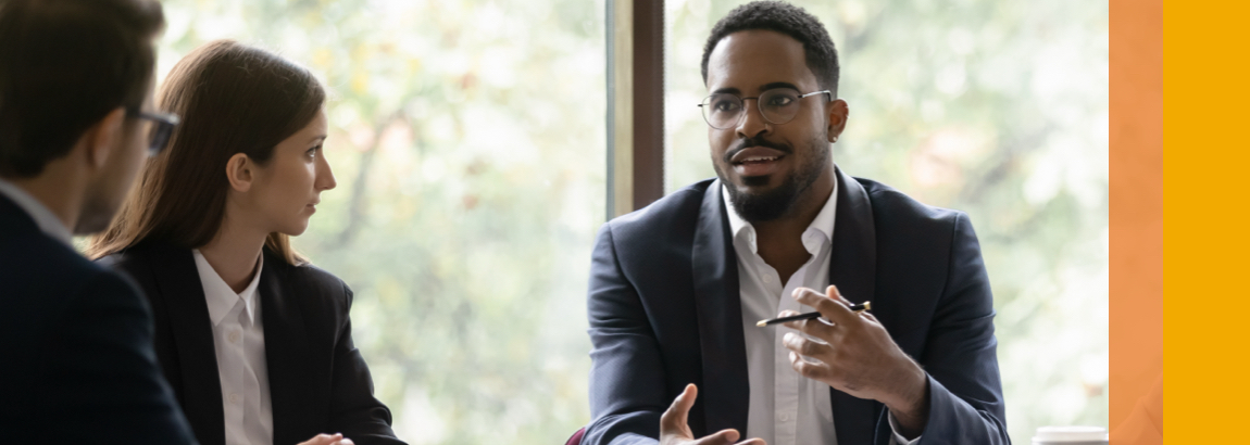 A young man talking to colleagues in a meeting